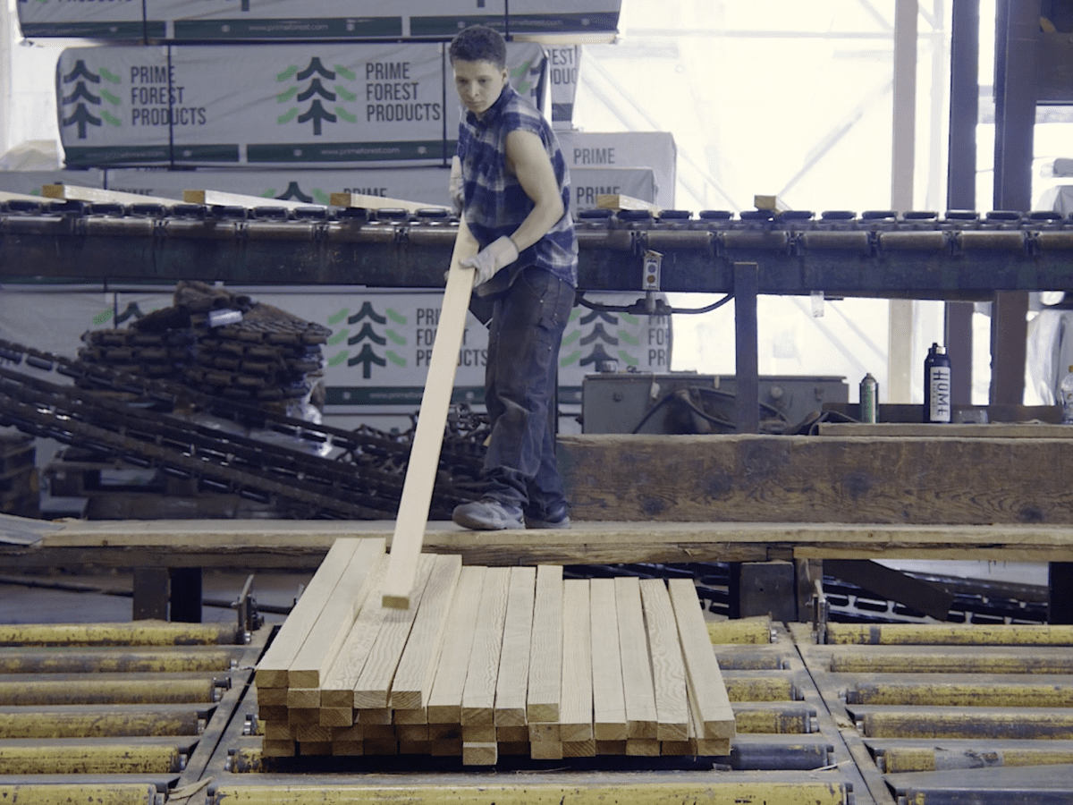 Prime Forest Products employee stacking lumber off of the chain