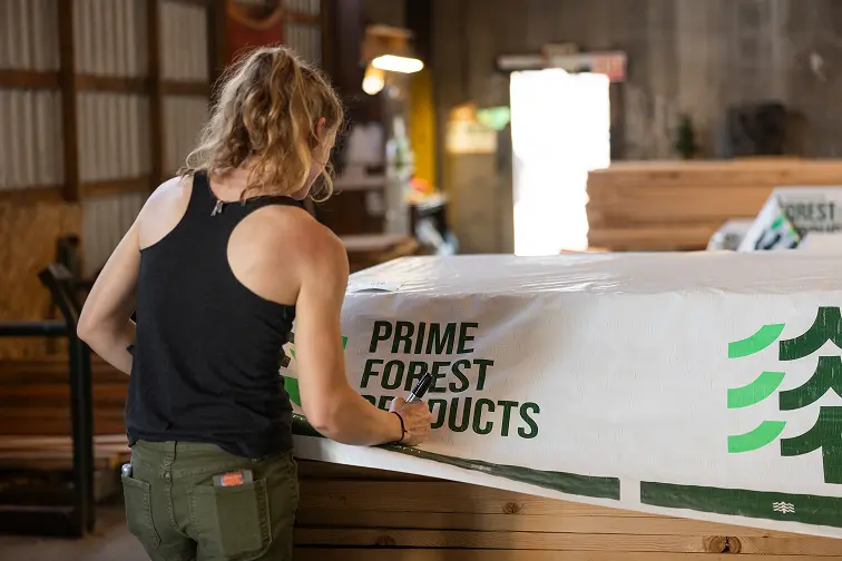 Prime Forest Products employee inspecting lumber stack before wrapping for shipping